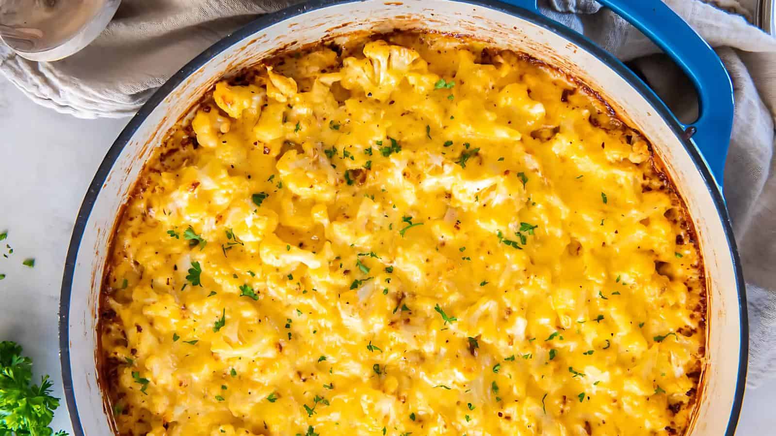 A large blue baking dish filled with golden-brown baked macaroni and cheese topped with fresh parsley.