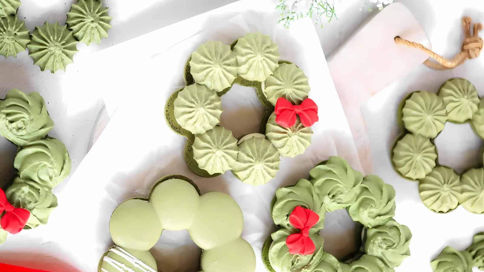 Green wreath-shaped desserts with red bow decorations on a white background.