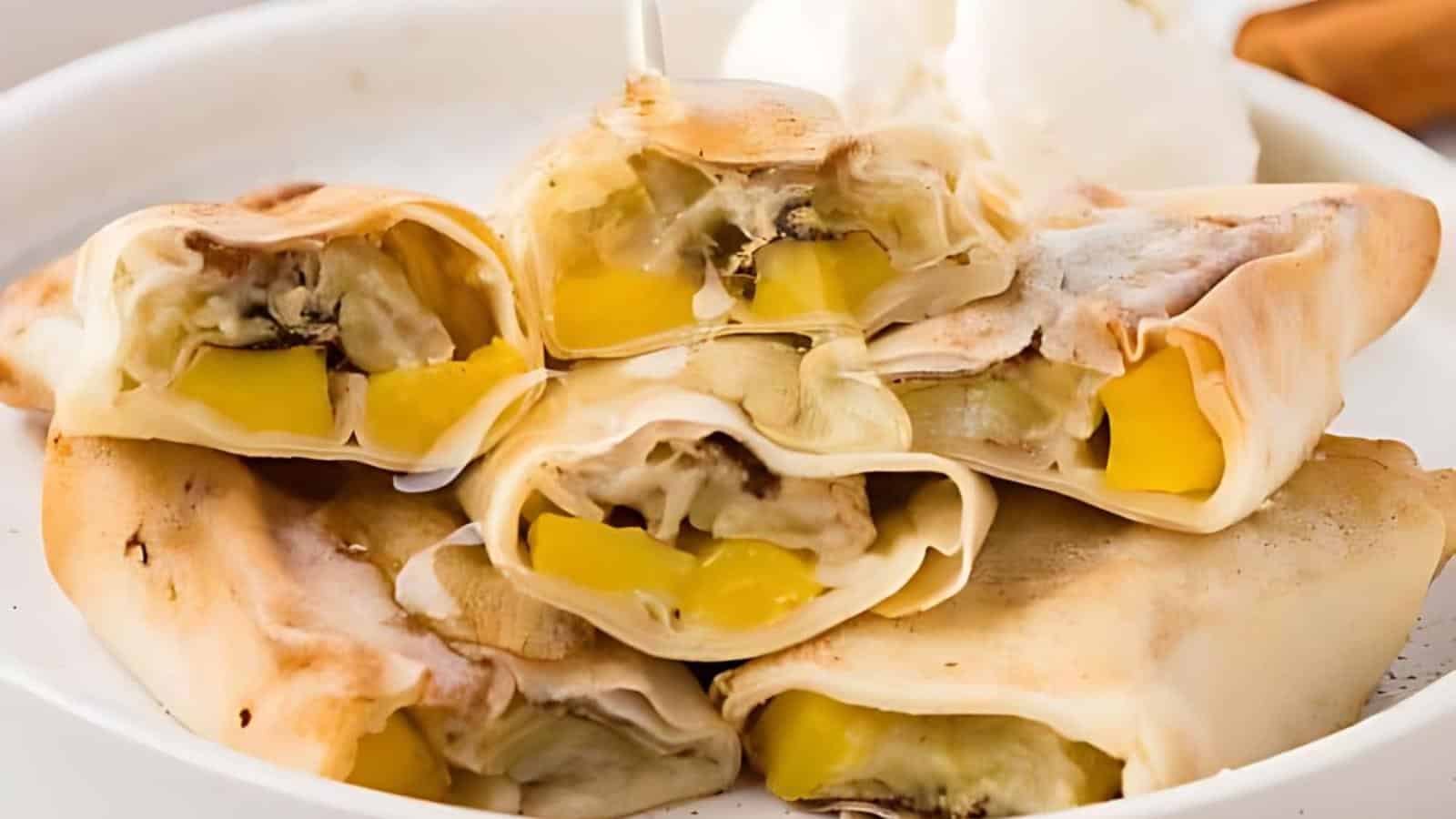 Folded pastries filled with banana and mango chunks, served on a white plate with a scoop of ice cream.