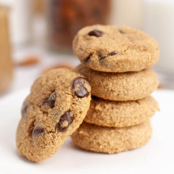 Stack of five chocolate chip cookies on a white plate.