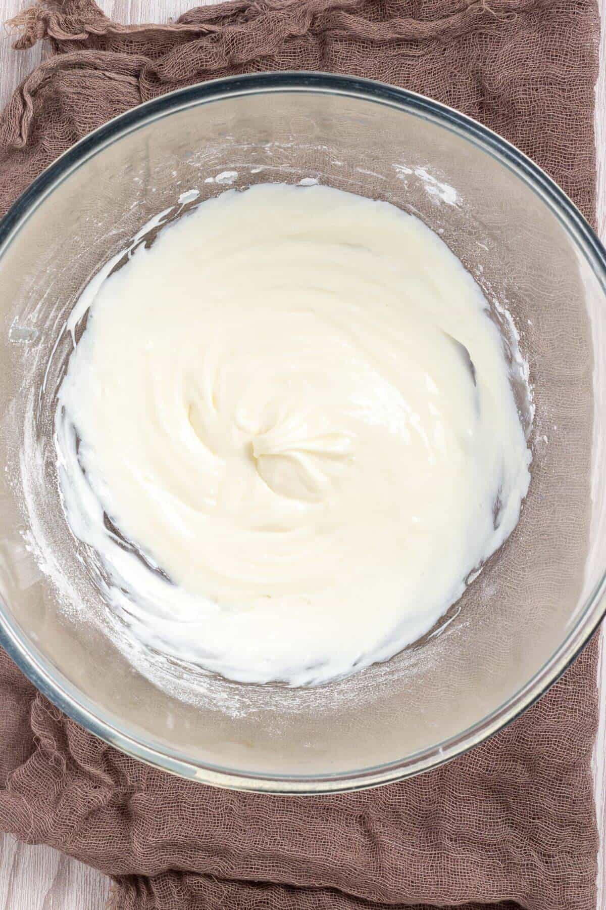 A glass bowl filled with smooth, creamy white mixture on a brown cloth.