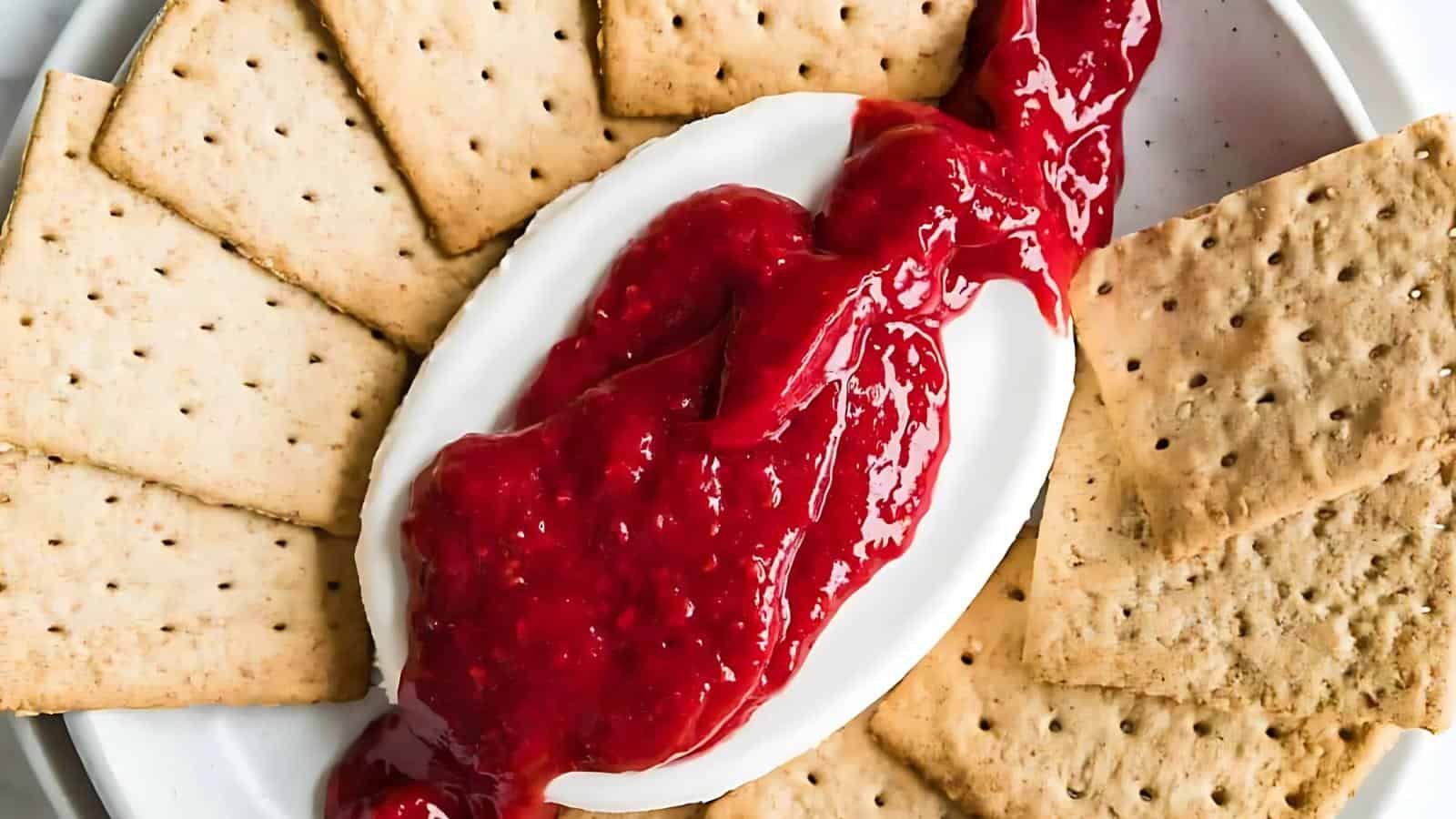 Crackers arranged around a plate with a white sauce and red sauce on top.