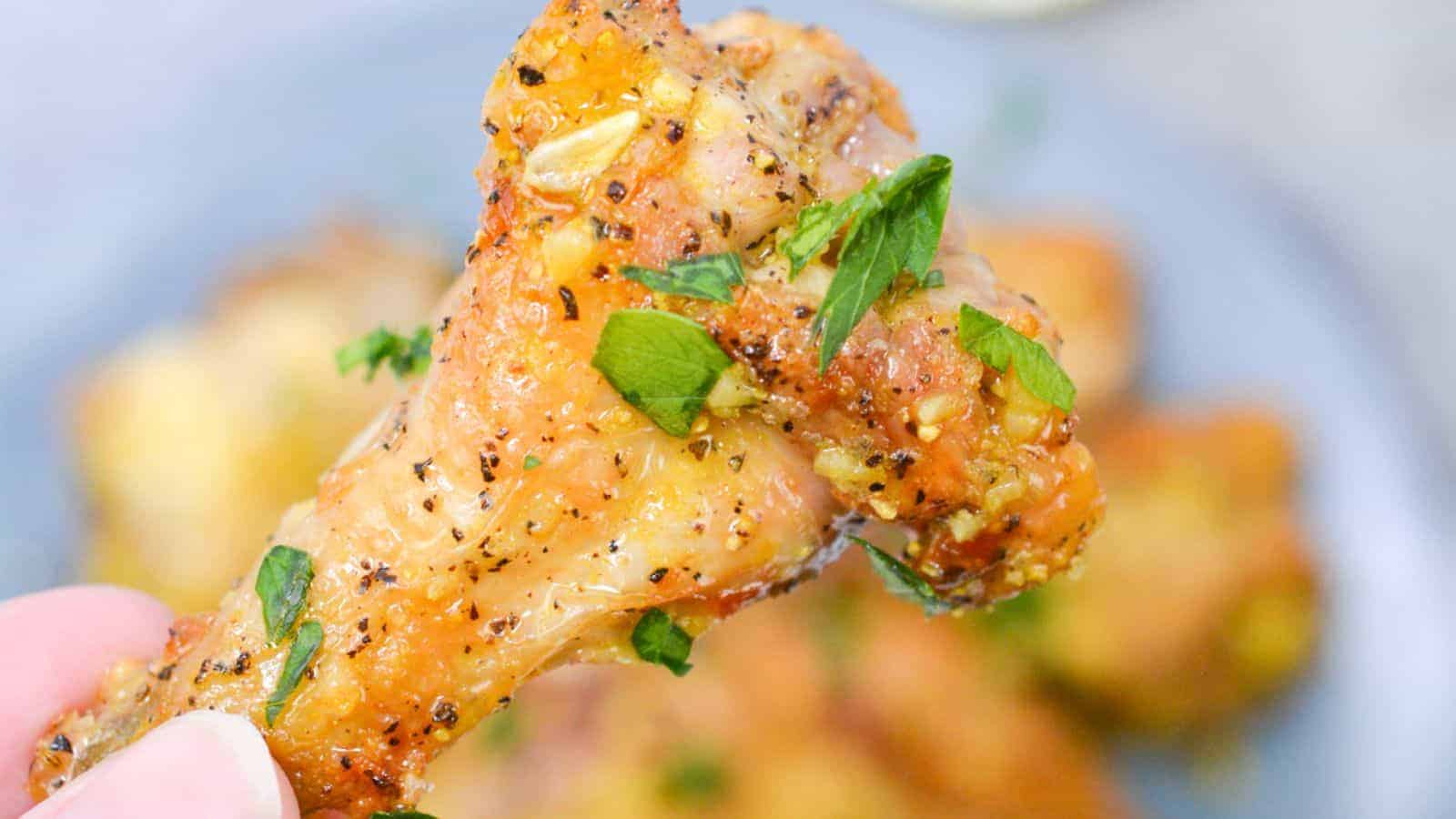 Close-up of a seasoned chicken wing garnished with chopped parsley.