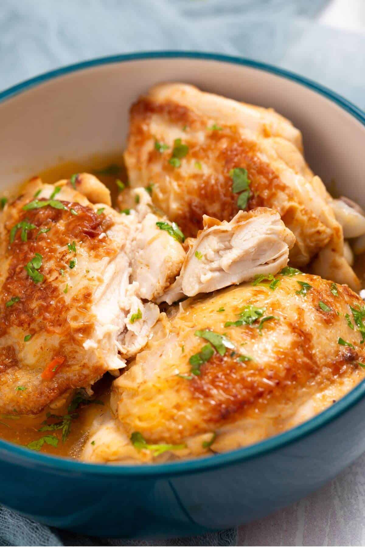 A bowl filled with cooked, golden-brown chicken pieces garnished with chopped herbs.