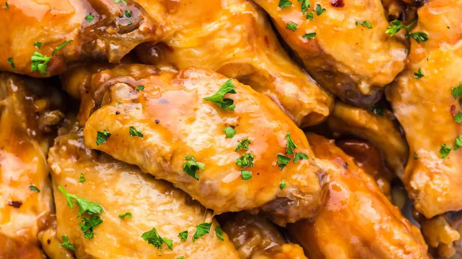 Close-up of glazed chicken wings topped with chopped parsley.