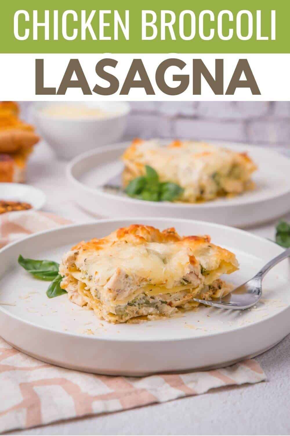 A slice of chicken broccoli lasagna on a white plate, garnished with basil, with another plate and food items in the background.