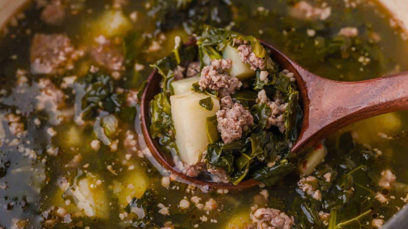 Soup with minced meat, greens, and diced potatoes in a wooden ladle.