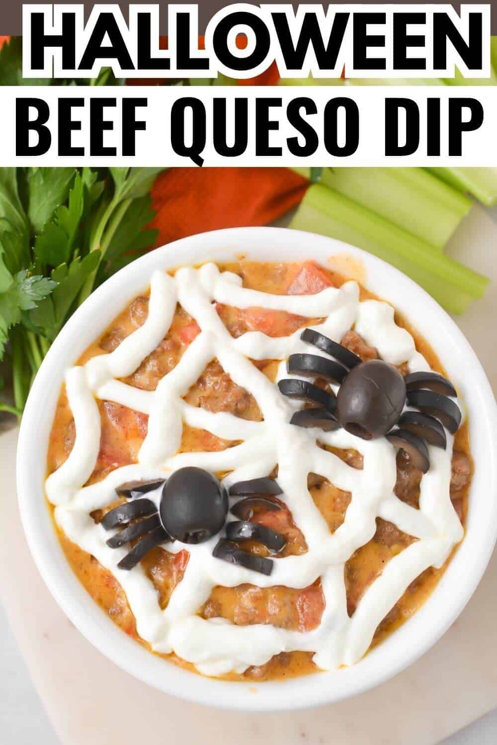 Bowl of beef queso dip topped with sour cream in a spider web pattern and two black olive spiders. Garnished with parsley and celery sticks nearby.