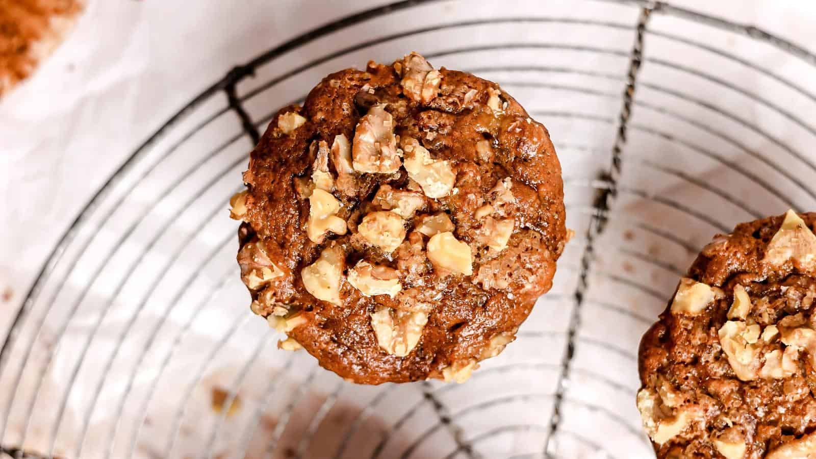 Close-up of a muffin topped with chopped nuts on a wire cooling rack.