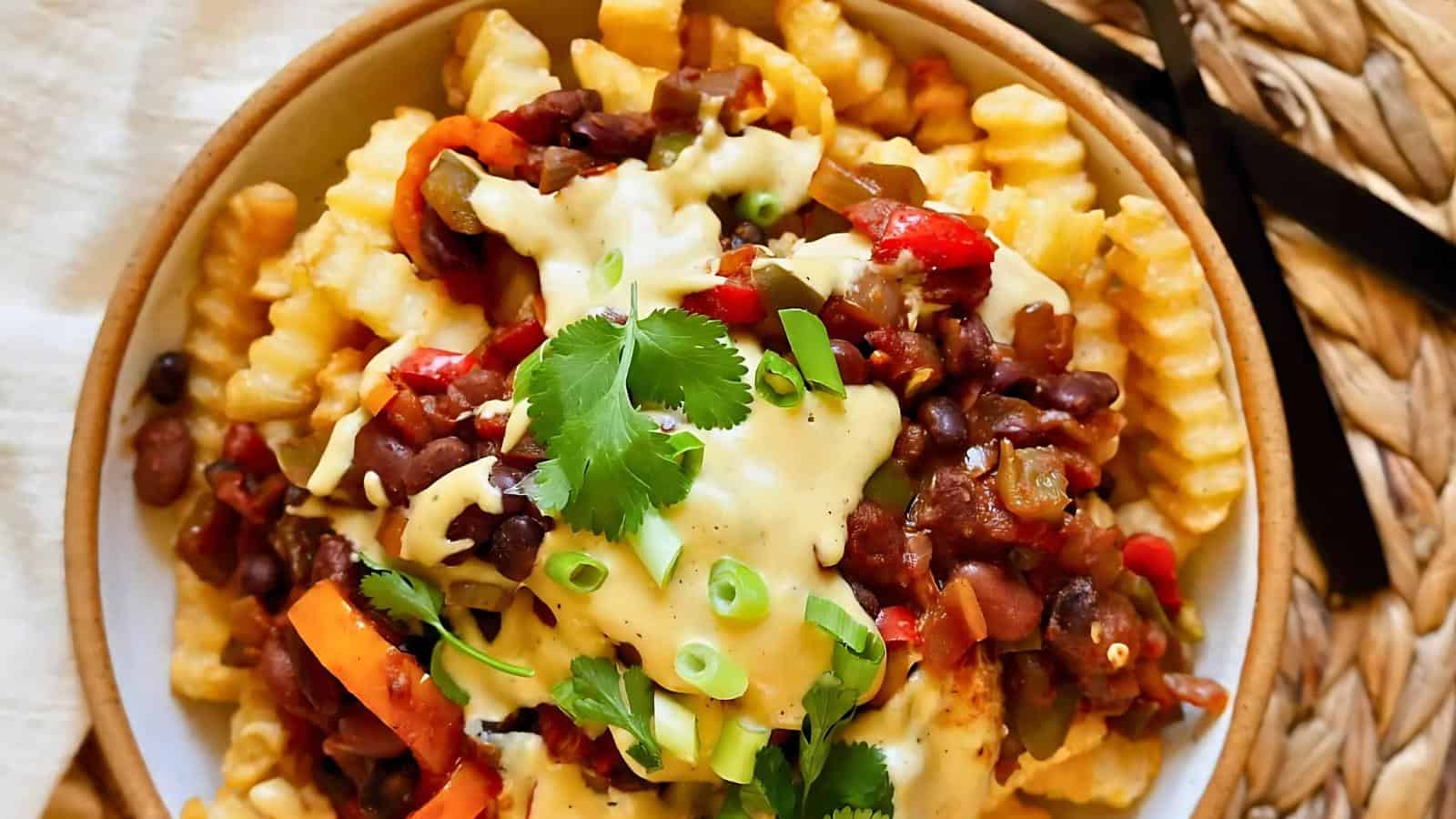 A plate of crinkle-cut fries topped with chili, melted cheese, sliced green onions, and cilantro.