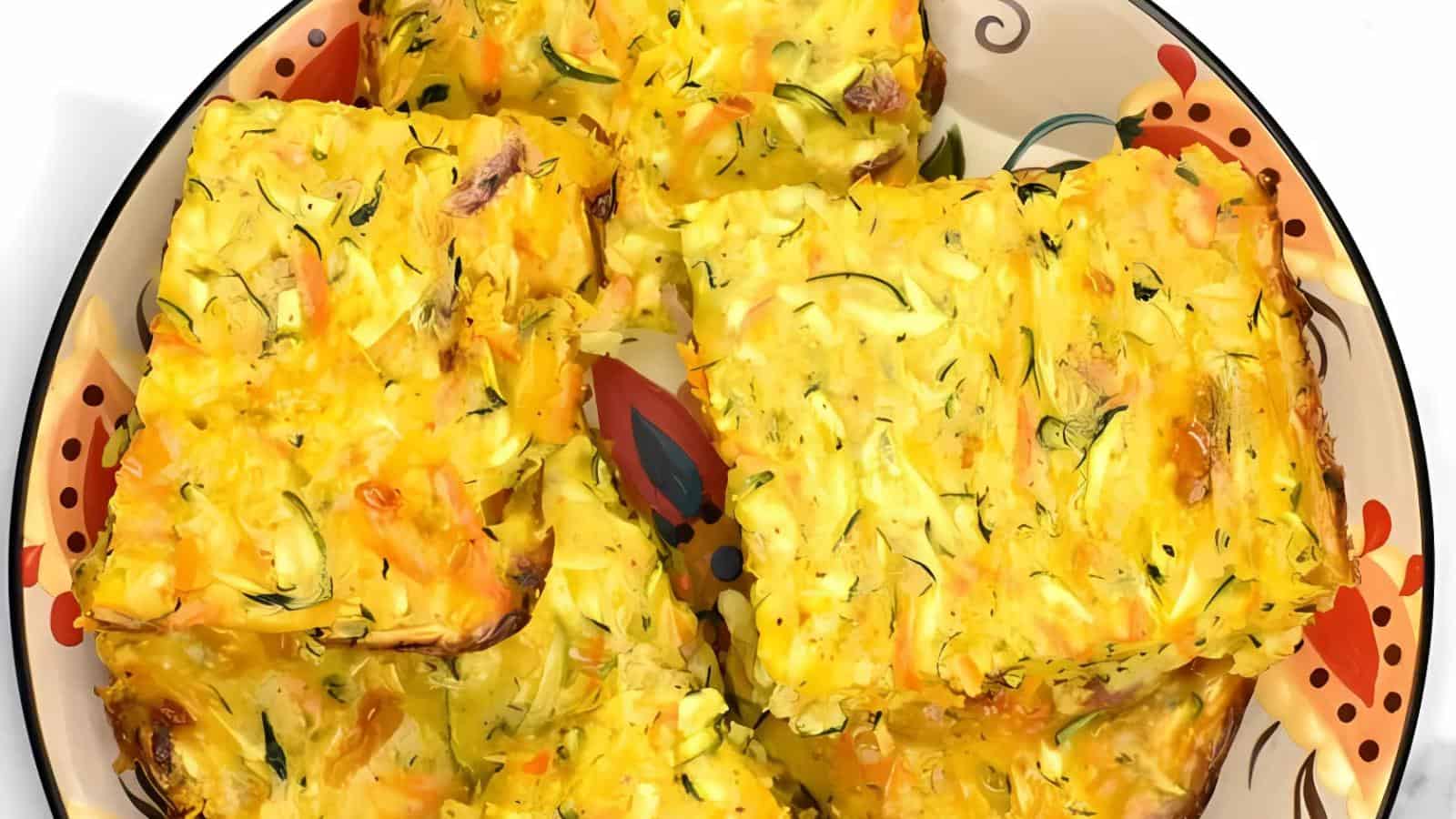 Four square pieces of zucchini slice on a decorative plate.