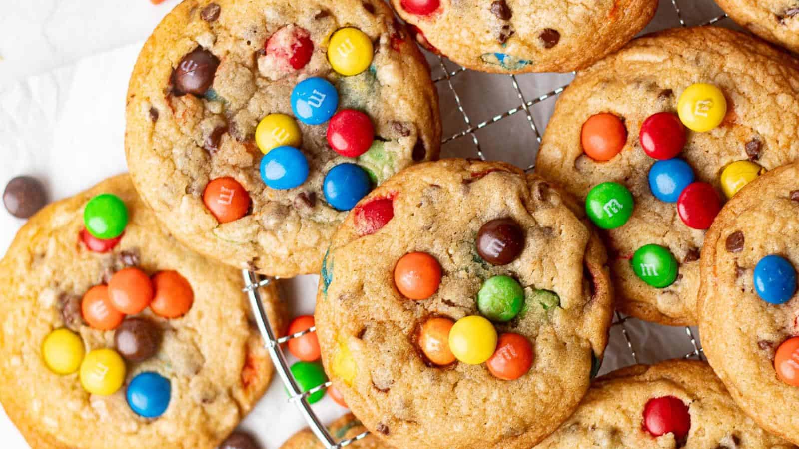 Cookies with colorful candy-coated chocolates and chocolate chips on a cooling rack.