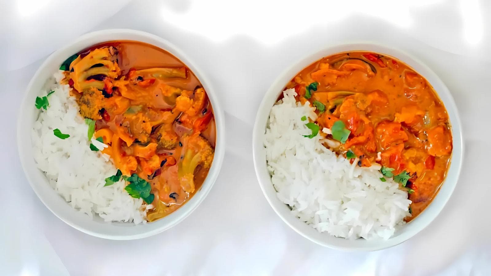 Two bowls of rice and vegetable curry garnished with cilantro, placed against a white background.