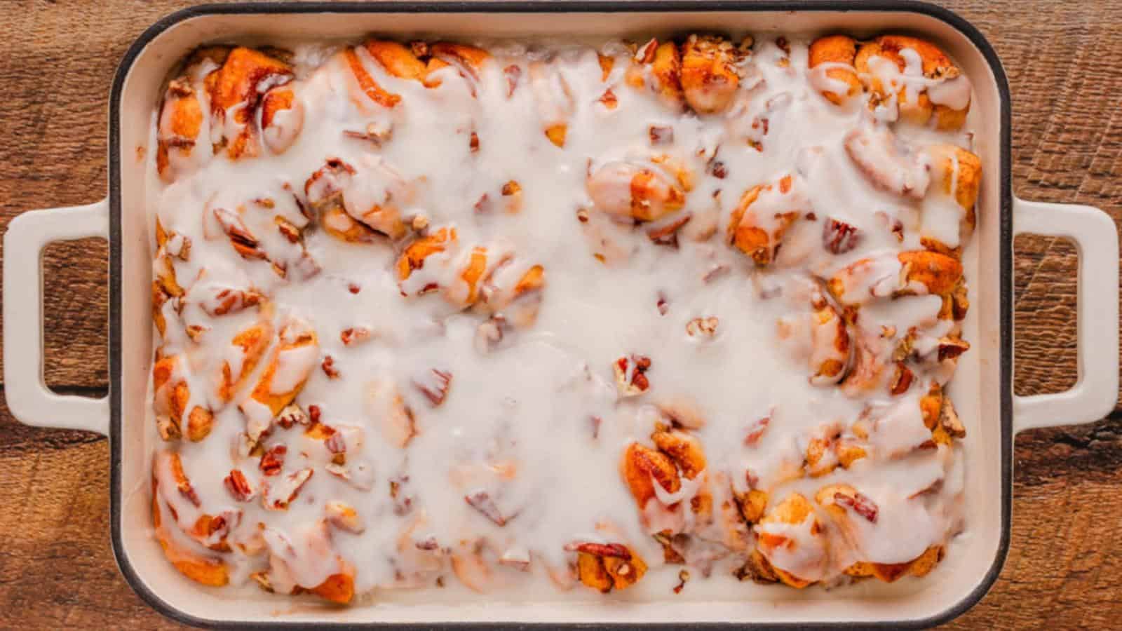 A baking dish filled with cinnamon rolls covered in white icing.