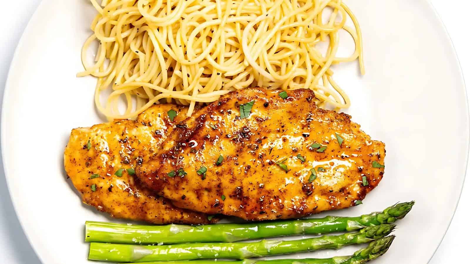 A plate with cooked spaghetti, two pieces of seasoned grilled chicken breast, and steamed asparagus spears.