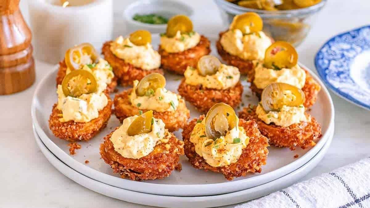 A plate with several deviled eggs that are deep fried.