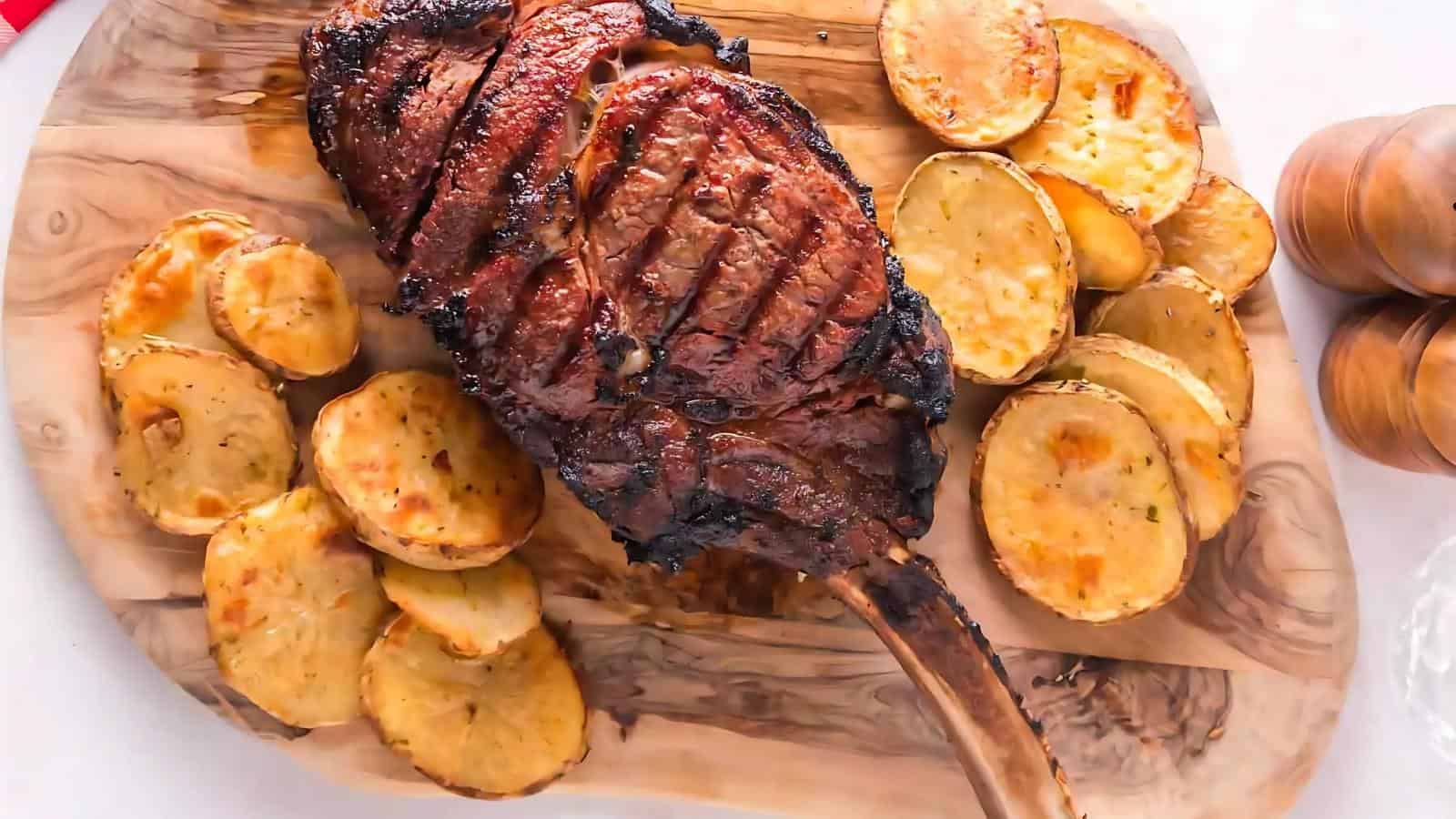 Grilled tomahawk steak with seared crosshatch marks served on a wooden board, surrounded by roasted potato slices.