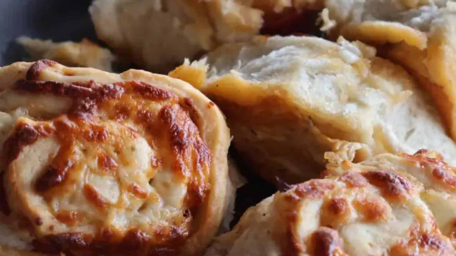 Close-up of freshly baked cheesy bread rolls with a golden-brown crust and visible melted cheese filling.