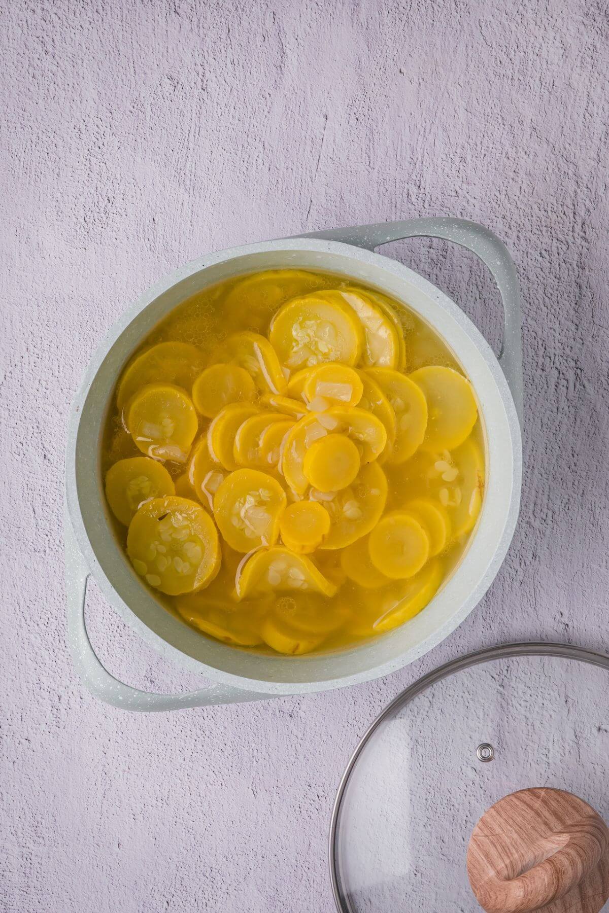 Squash, onion, broth, and avocado oil simmering in a pot