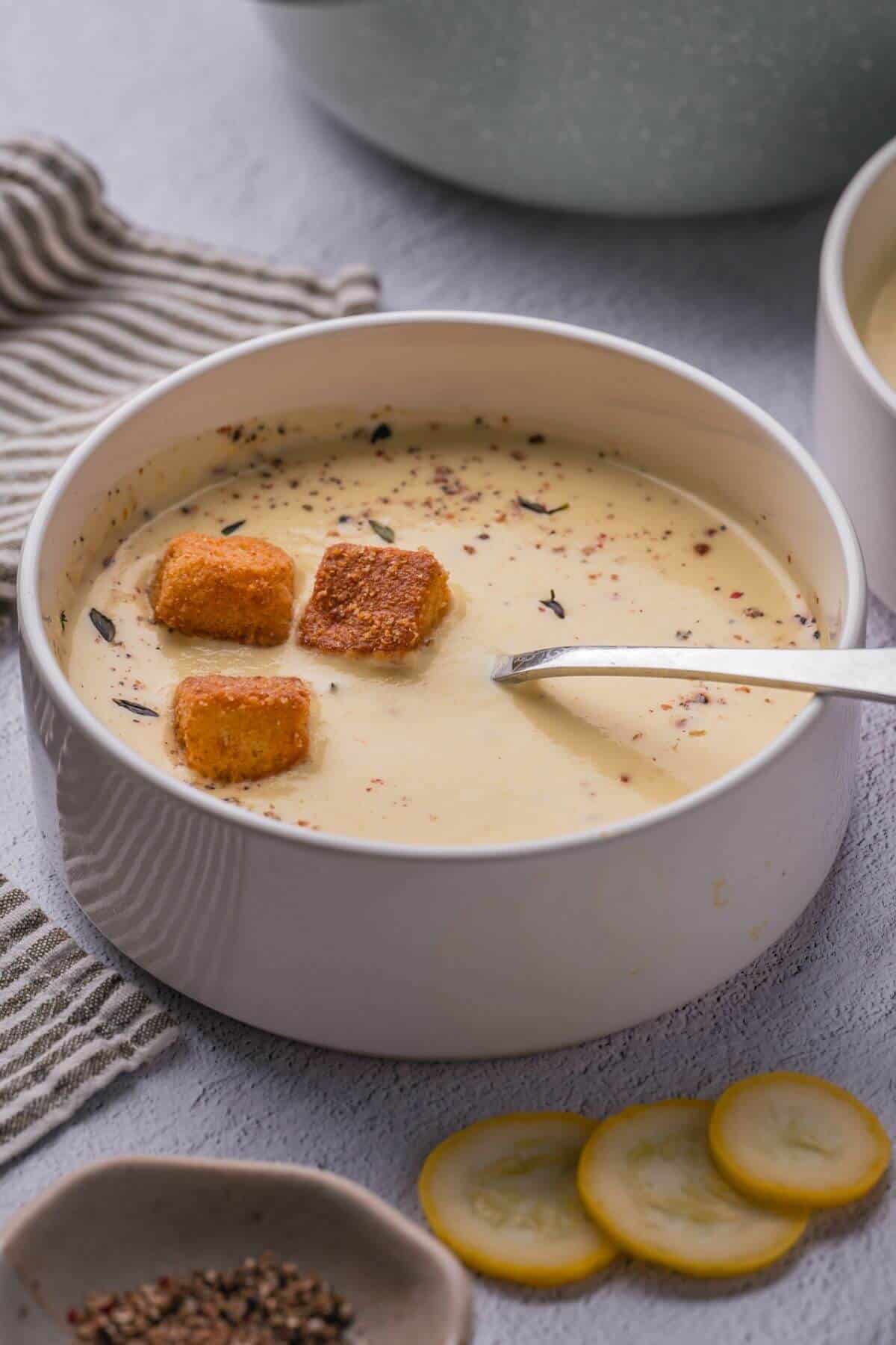 Bowl of yellow squash soup with a spoon