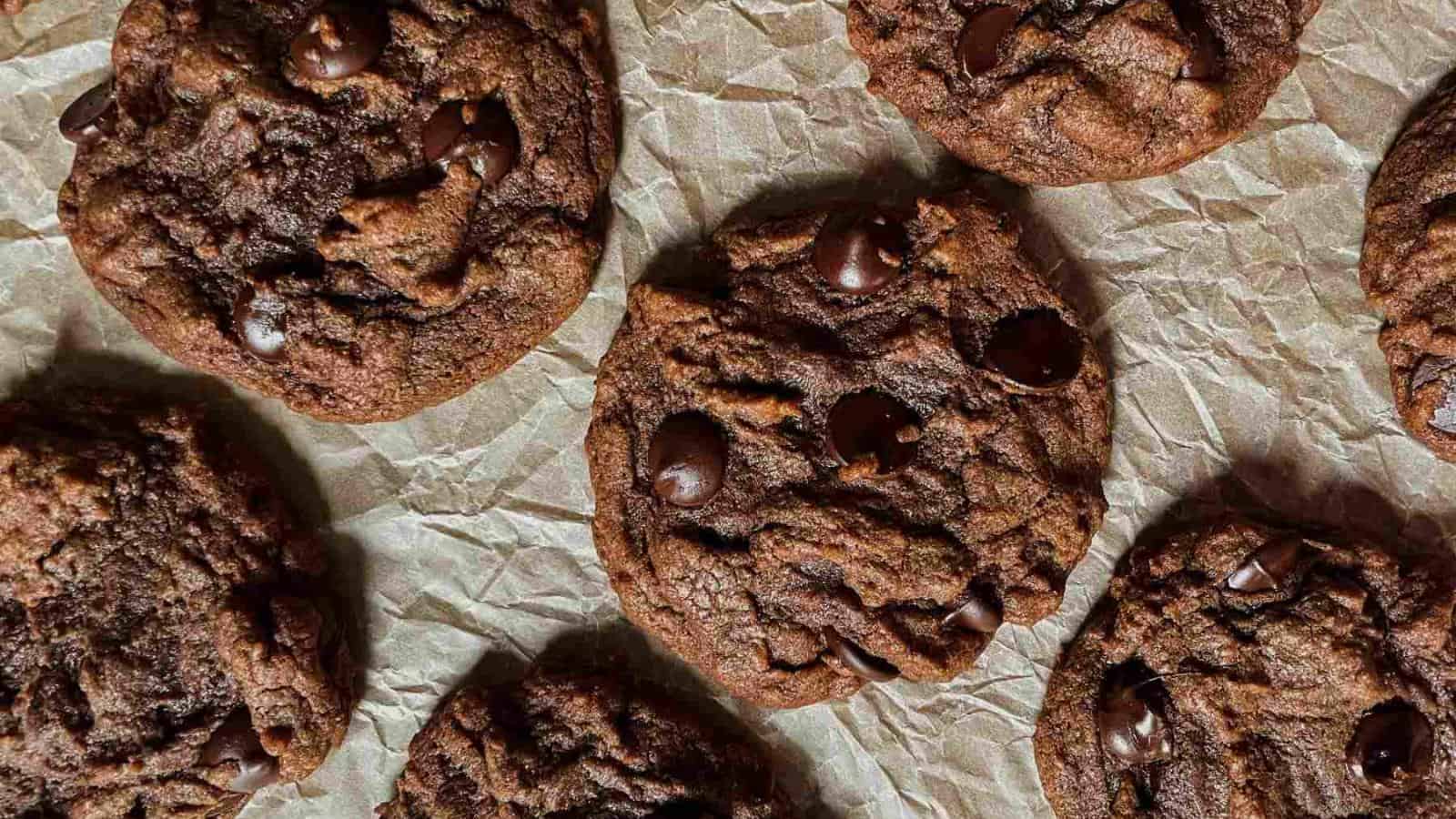 Several chocolate chip cookies are arranged on a sheet of crumpled parchment paper.