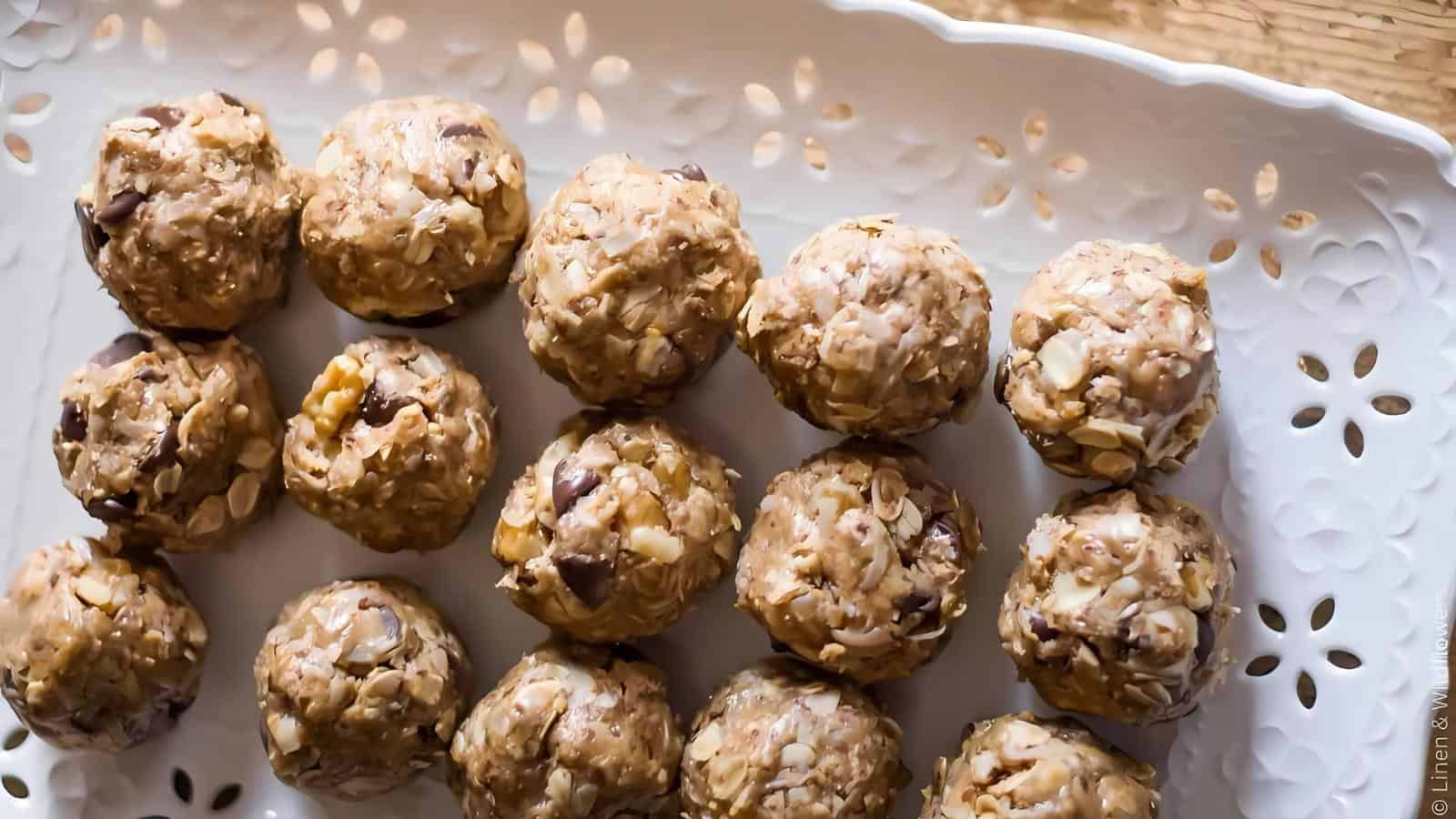 A white tray holds rows of round, no-bake energy bites made with oats, peanut butter, and chocolate chips.