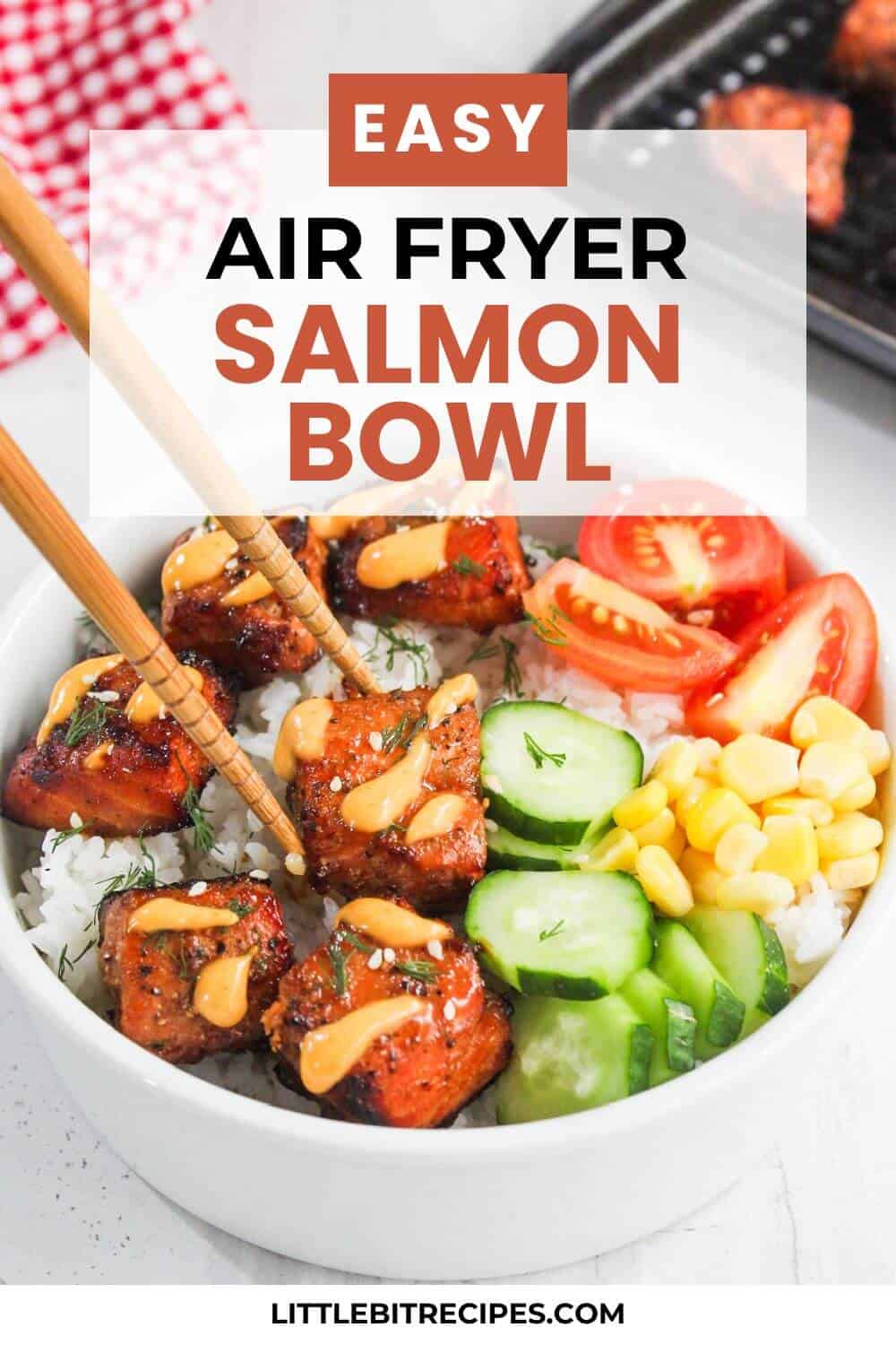 A bowl of rice topped with air fryer salmon bites, sliced cucumbers, cherry tomatoes, corn, and a drizzle of sauce, with chopsticks resting on the bowl.