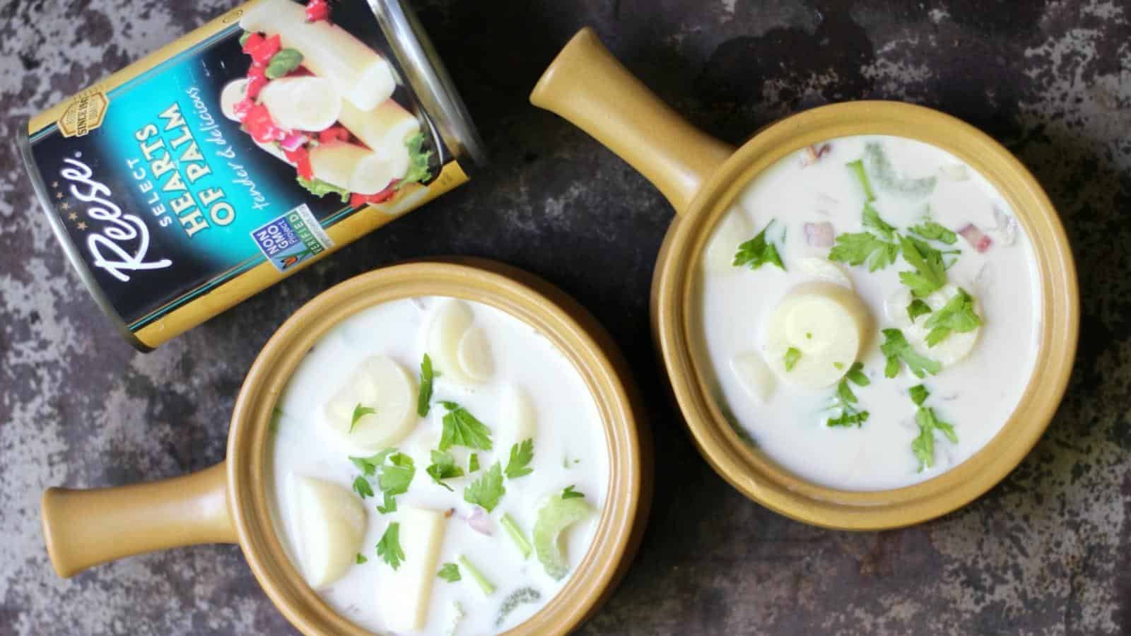 Two bowls of creamy soup with hearts of palm and parsley, next to an open can labeled "Hearts of Palm.