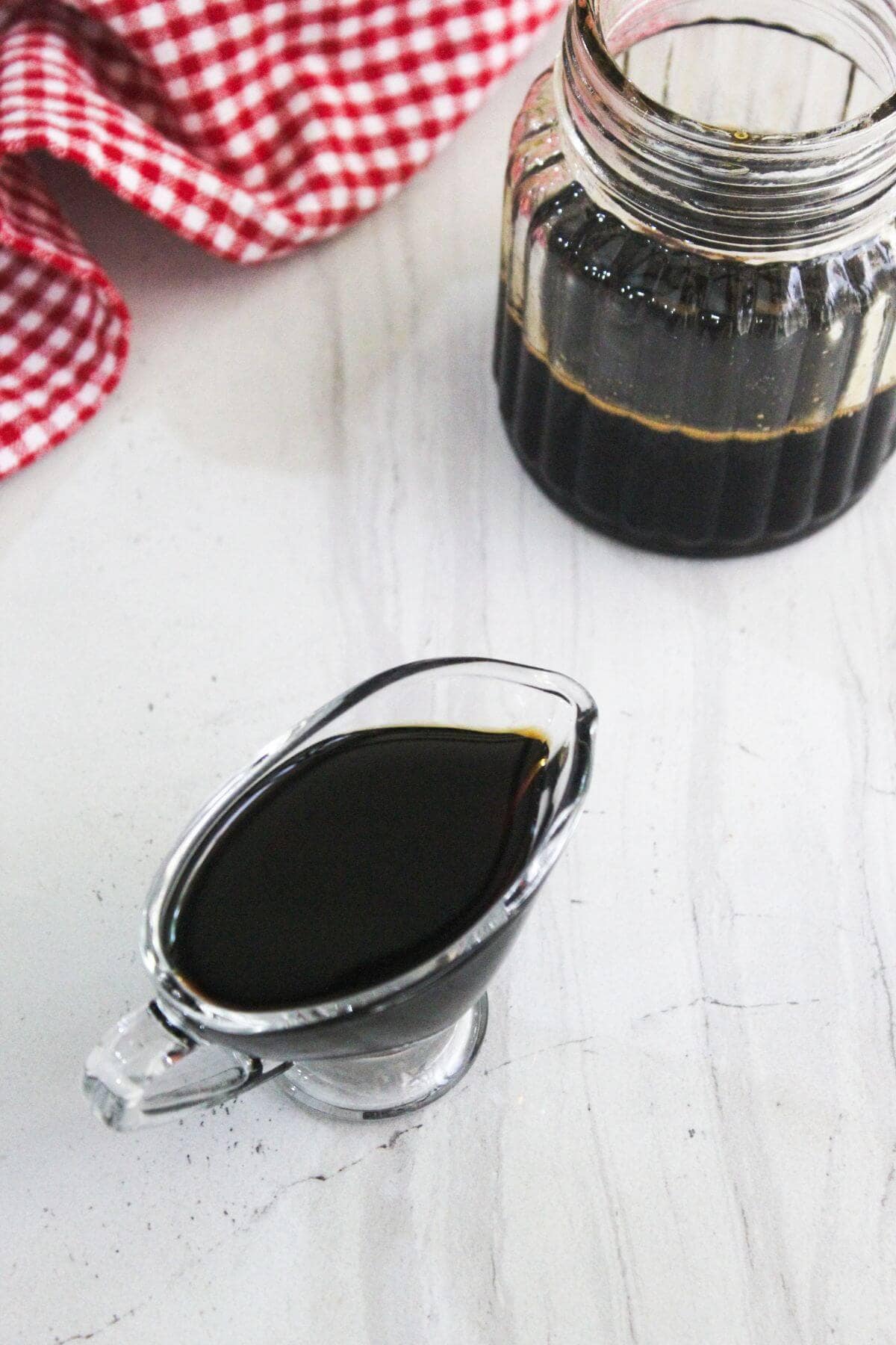 A glass gravy boat with a liquid in it.