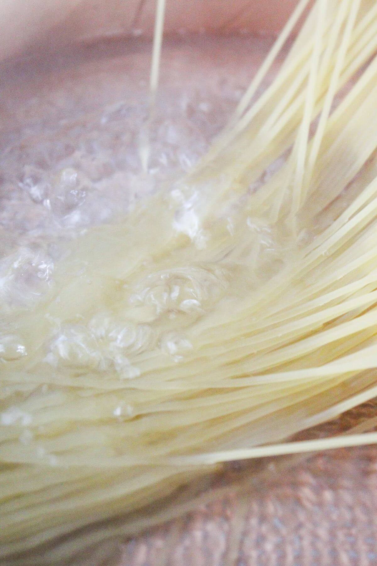 Uncooked spaghetti noodles being added to a pot of boiling water.