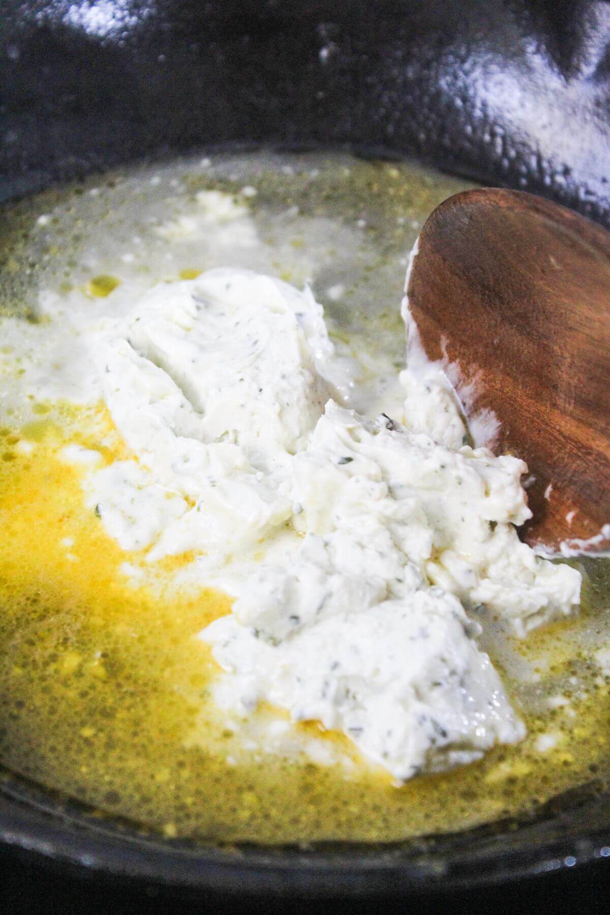 A spoon stirring food in a pan.