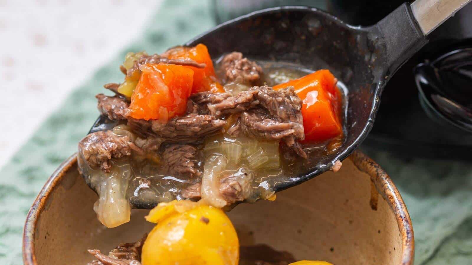A ladle serves beef stew with shredded beef, carrots, onions, and potatoes into a bowl.