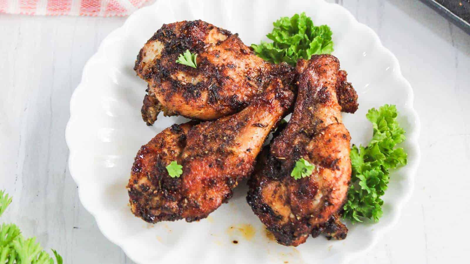 Three pieces of seasoned, grilled chicken are served on a white plate, garnished with parsley.