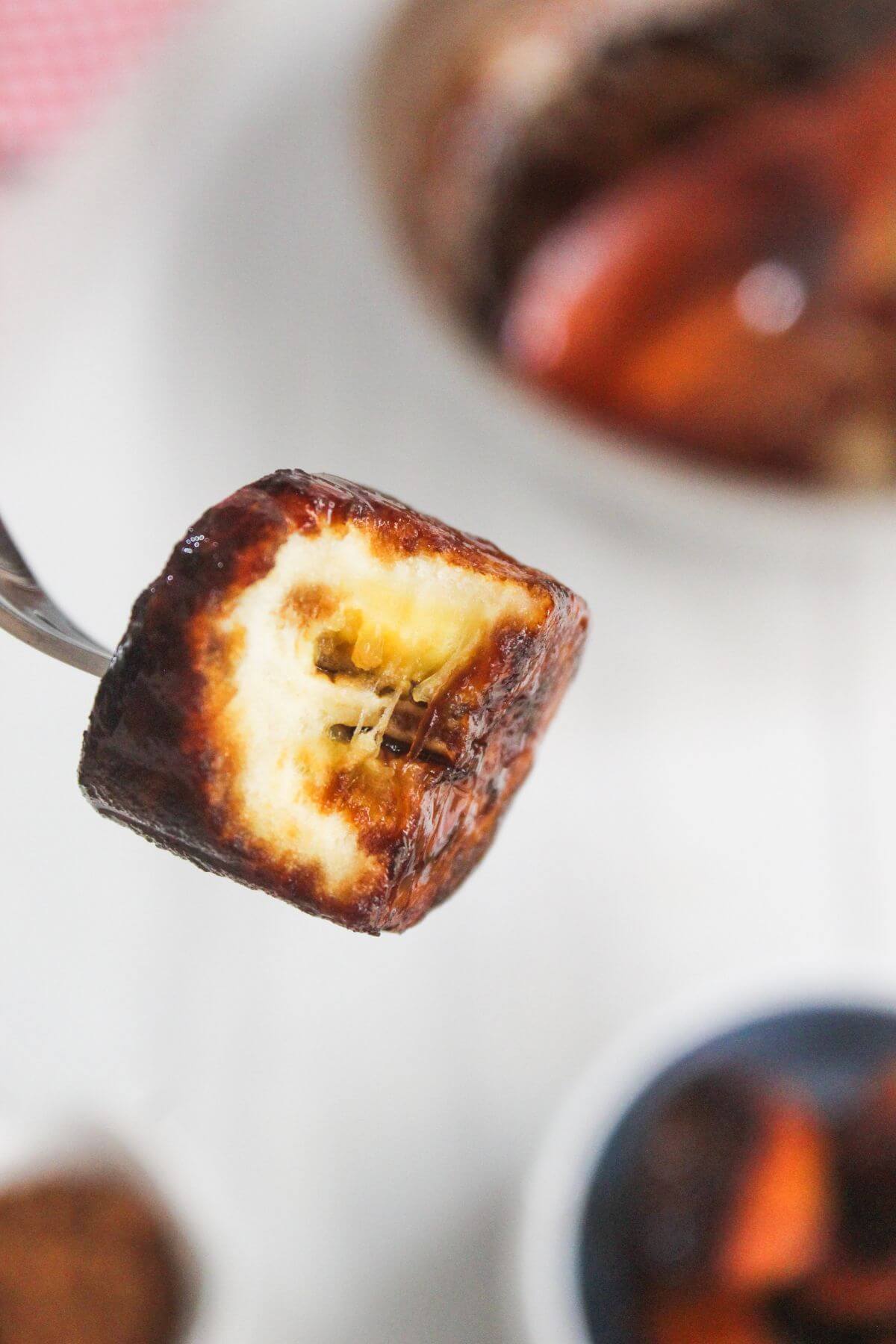 A fork holds a toasted marshmallow with a melted, gooey center and a browned, caramelized exterior.